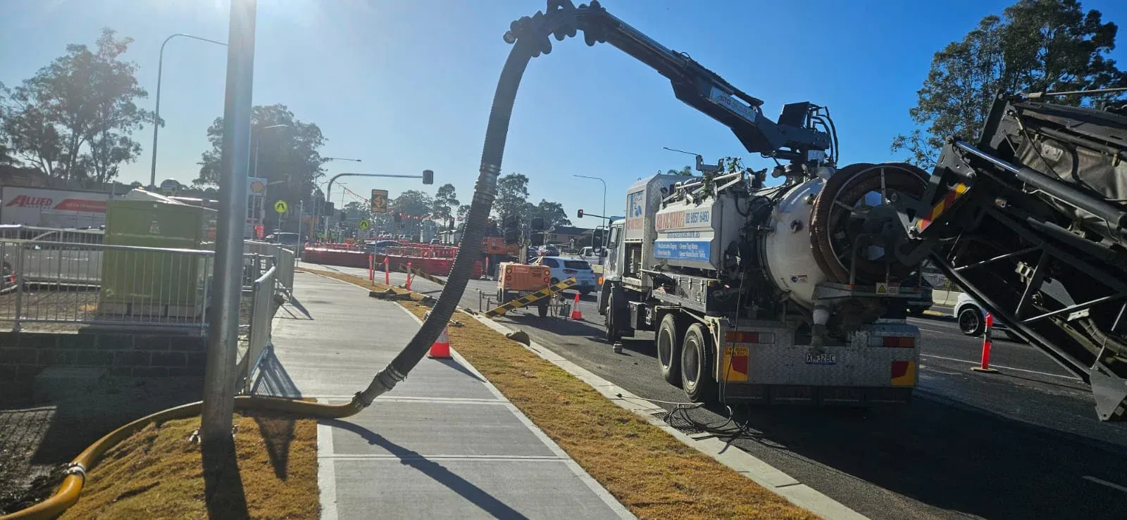 ASB Vac Services vacuum truck on infrastructure project — boom extended, golden hour