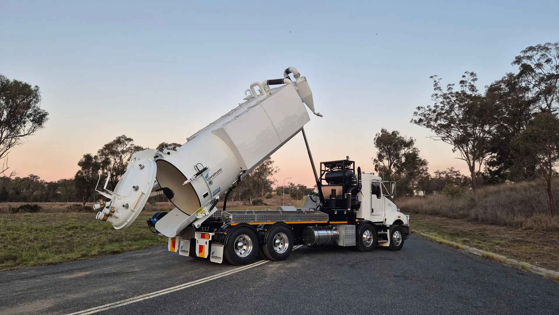 Rear view of the finished truck at dusk with the tank raised and the full-width rear door open