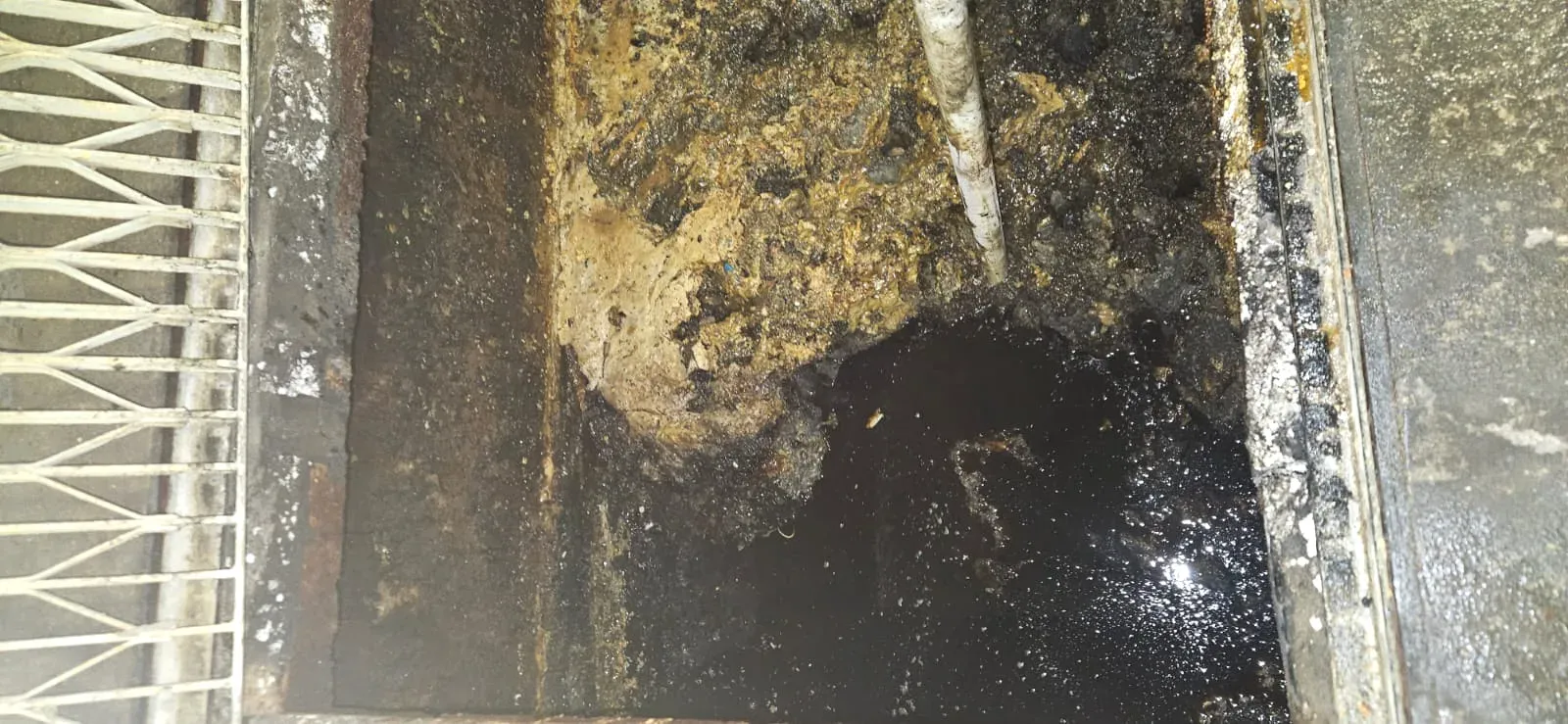 Commercial grease trap with heavy hardened grease buildup before cleaning