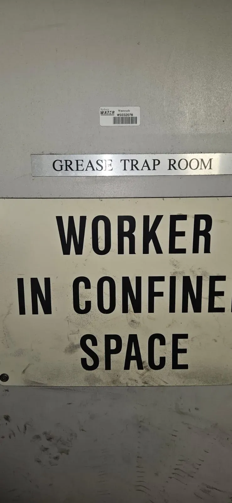 Grease trap room signage with confined space warning at a commercial plant room