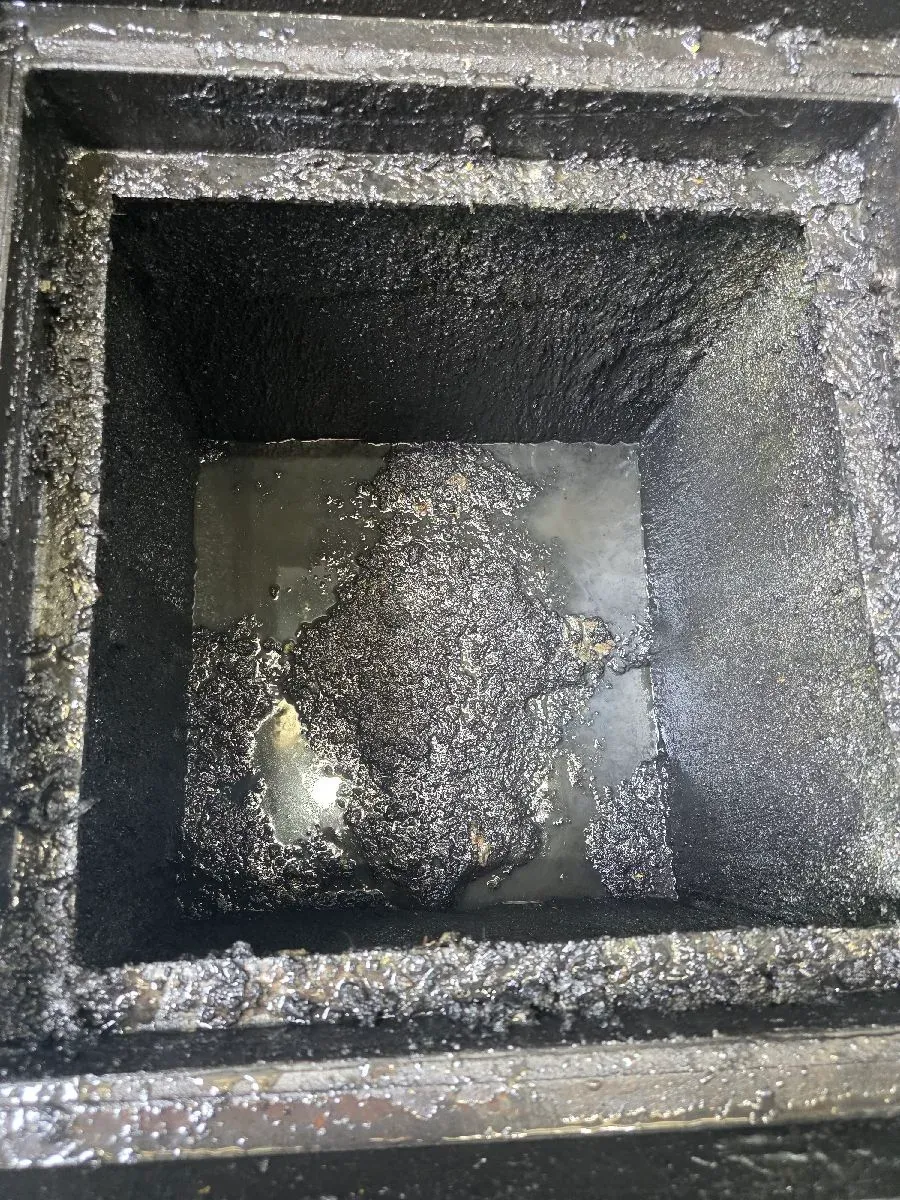 Pit walls coated in black hydrocarbon sludge before cleaning