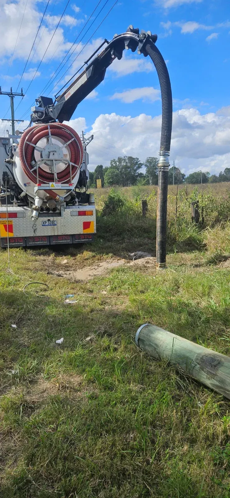 ASB vacuum truck boom hose excavating beside a power pole on a rural roadside — non-destructive digging for pole replacement