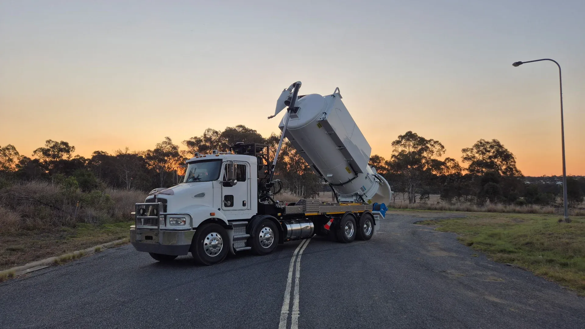 ASB Vac Services' 13,500L HydroVac parked at dusk with its tipping tank raised