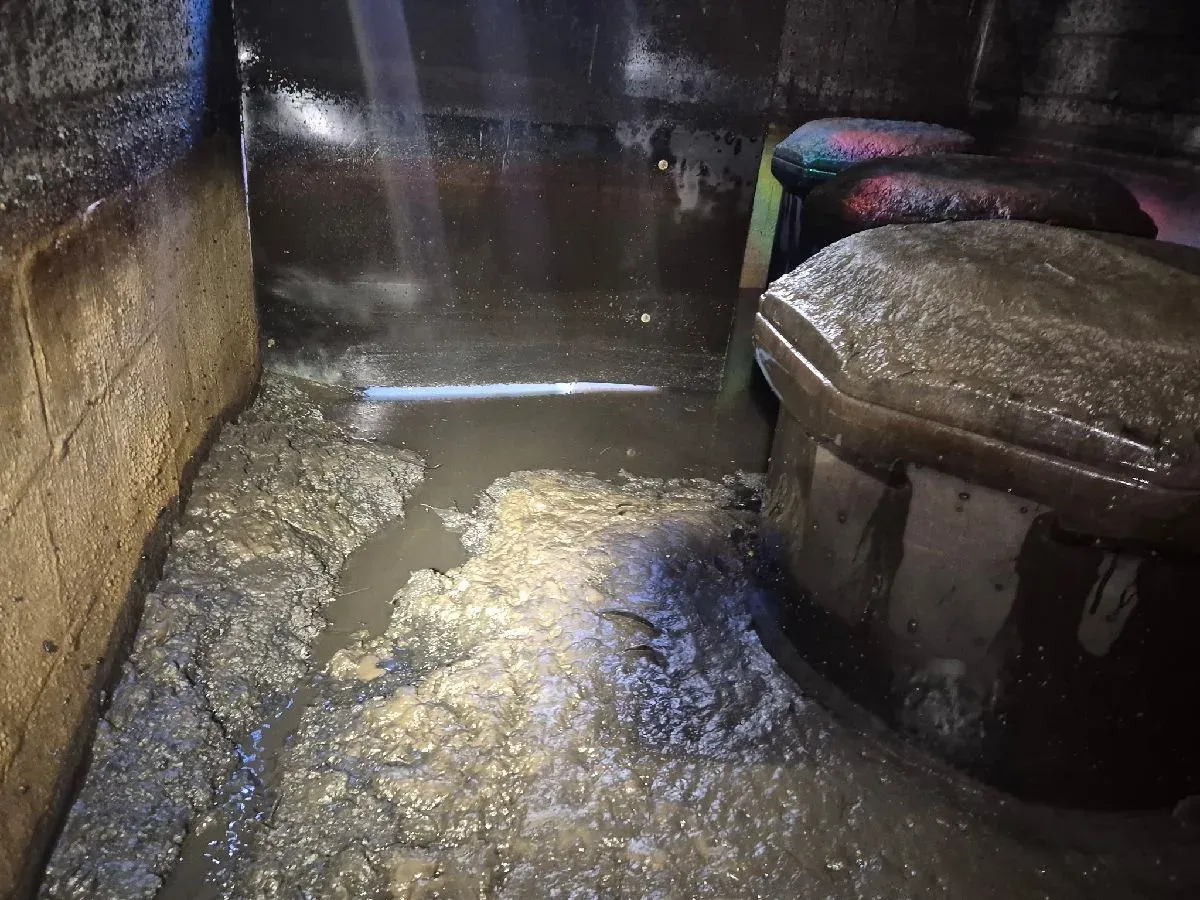 Thick sludge banked inside a stormwater tank before cleaning